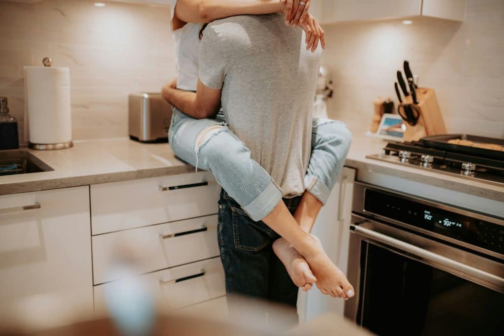 A picture of couple cuddling at the kitchen table.