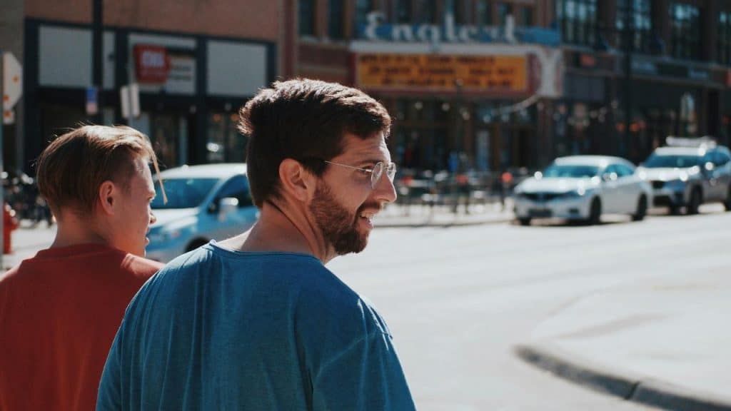 A man walking down a street with a friend.