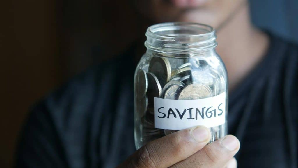 A glass jar labeled “Savings” filled with coins.