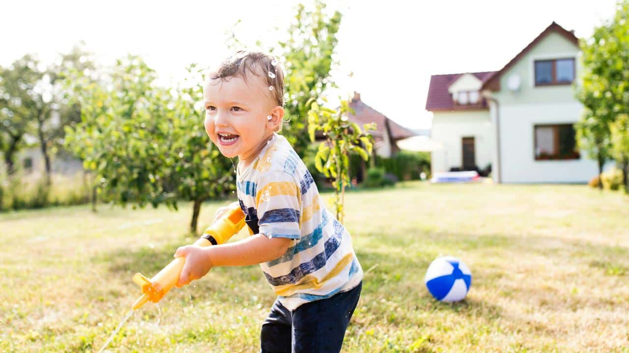 A young boy spraying water with a water gun outdoors.