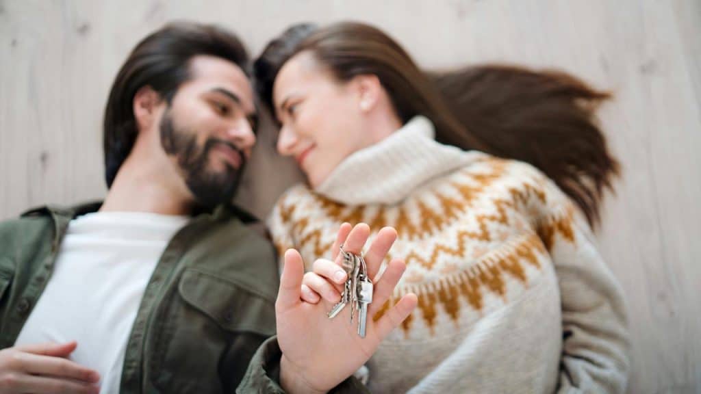 A couple lying on the floor holding a set of keys.