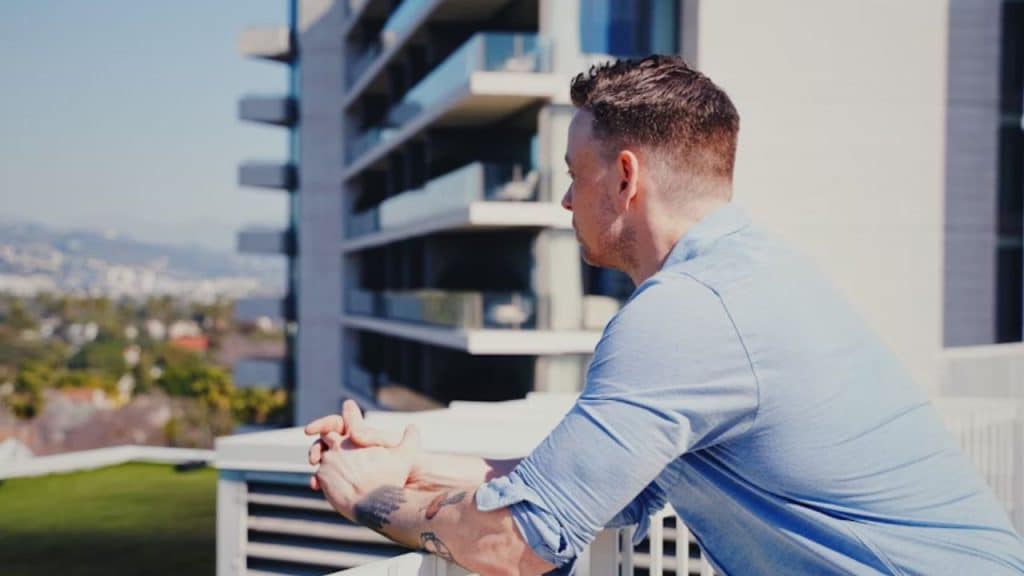 Man standing on a balcony in morning sunlight.