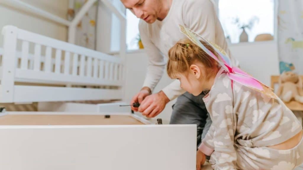 Dad fixing something at home while child watches and learns.