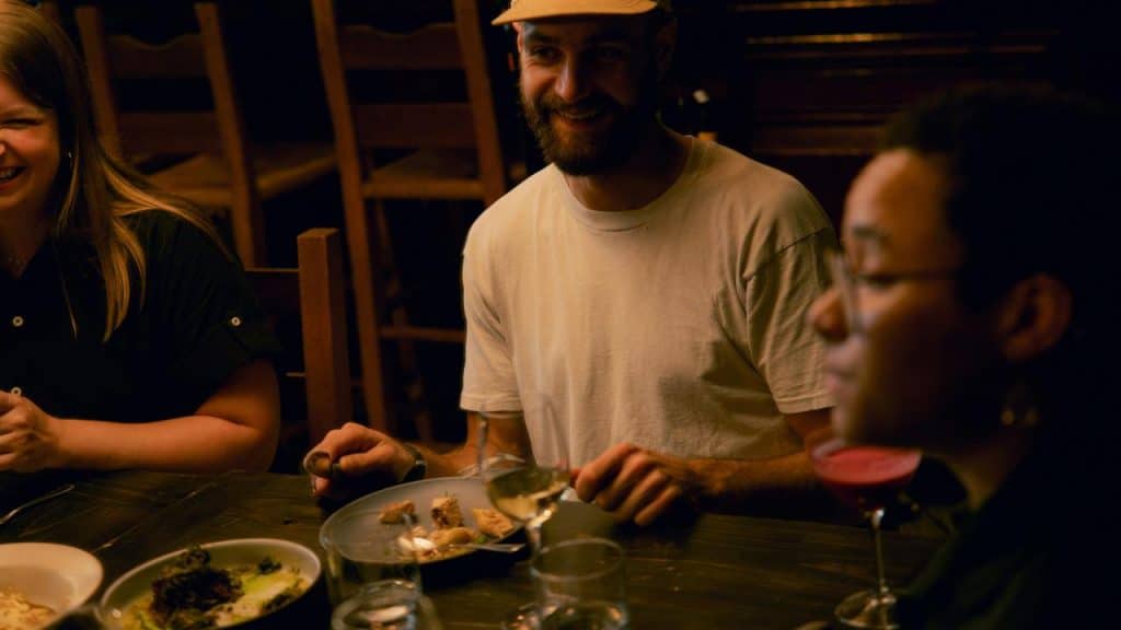 A group of friends enjoying dinner at a dimly lit table.