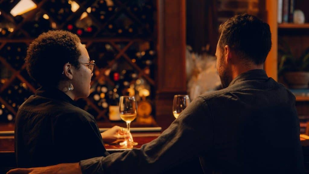 A couple seated at a wine bar holding glasses.
