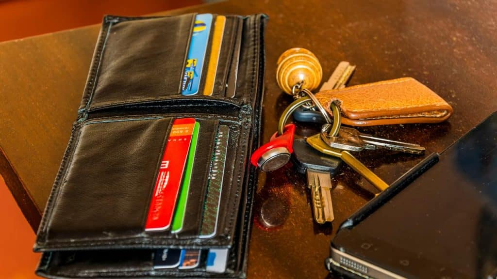 A wallet with cards next to a set of keys on a table.