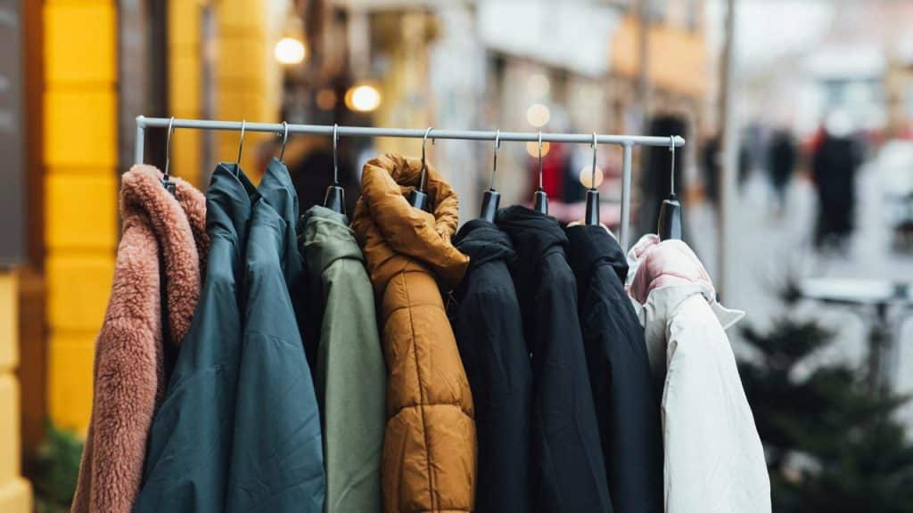 A row of winter coats hanging on an outdoor rack.
