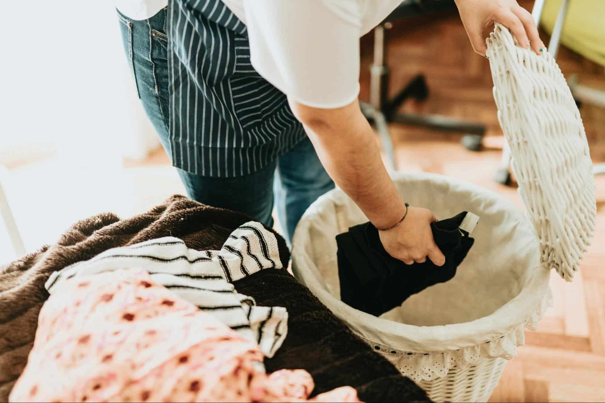 A man putting a cloth in a laundry basket.