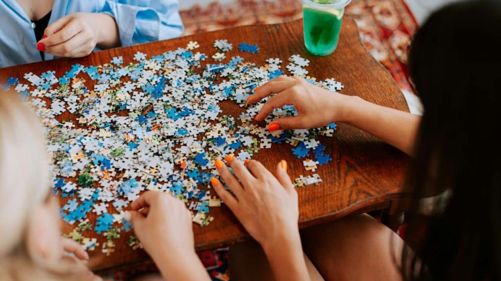 A few hands sorting jigsaw puzzle pieces.
