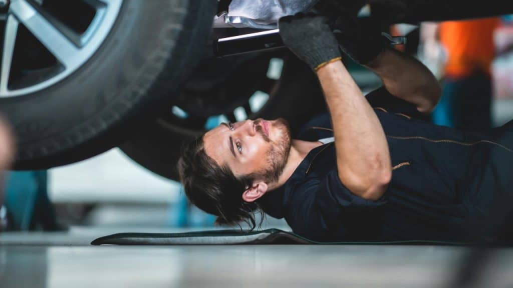 A mechanic working beneath a lifted car.