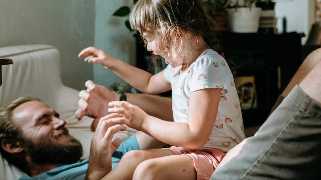 A man tickling a child on a couch.