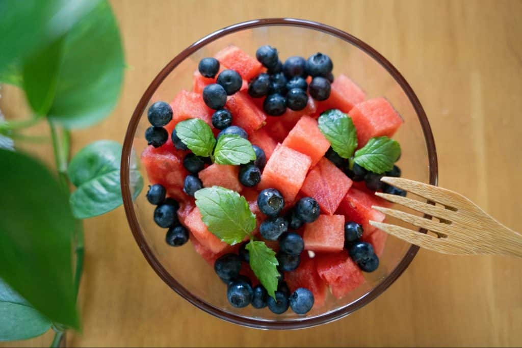 A picture of greens and berries on a bowl.