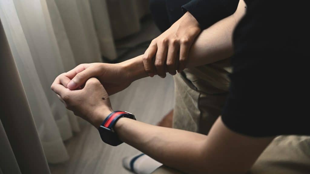 A woman holding her man’s wrist to comfort him