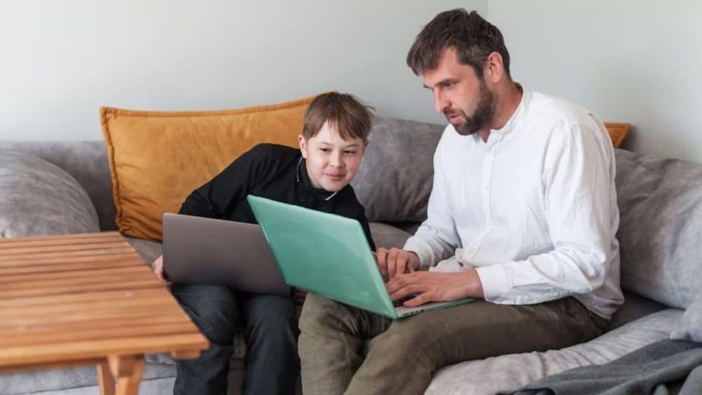 Dad and child researching something together on a laptop.