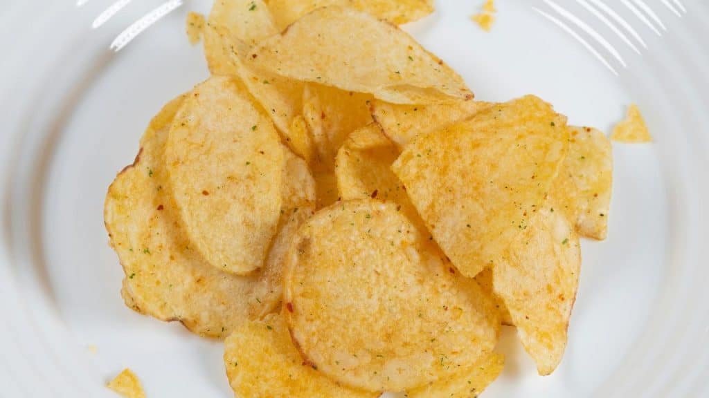 A pile of potato chips on a white plate.
