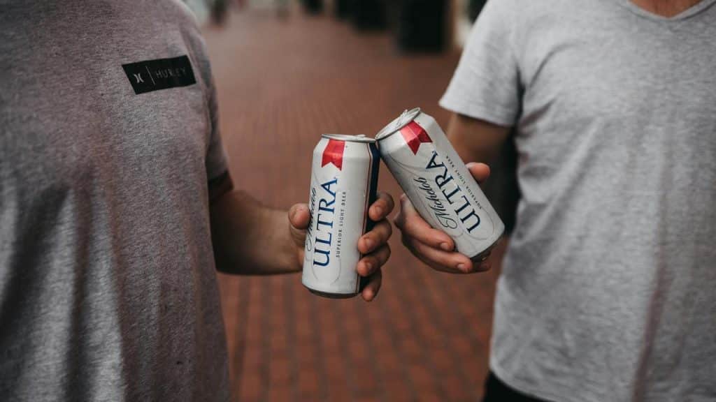 A pair of hands clinking beer cans.