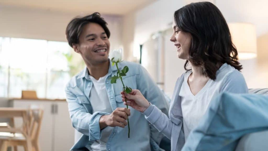 Man holding a  flower while woman seems unsure