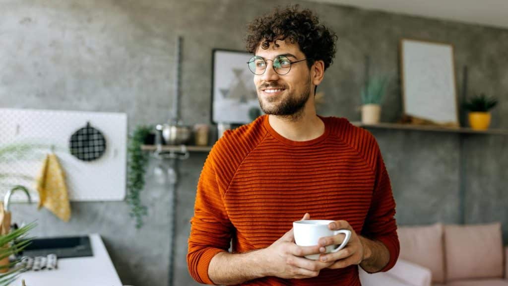 A man with glasses holding a coffee mug.