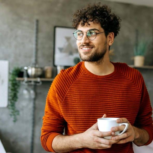 A man with glasses holding a coffee mug.