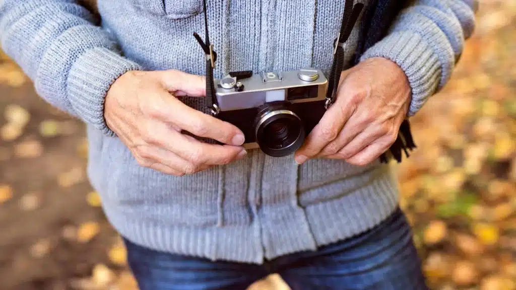 An elderly person holding a vintage film camera.