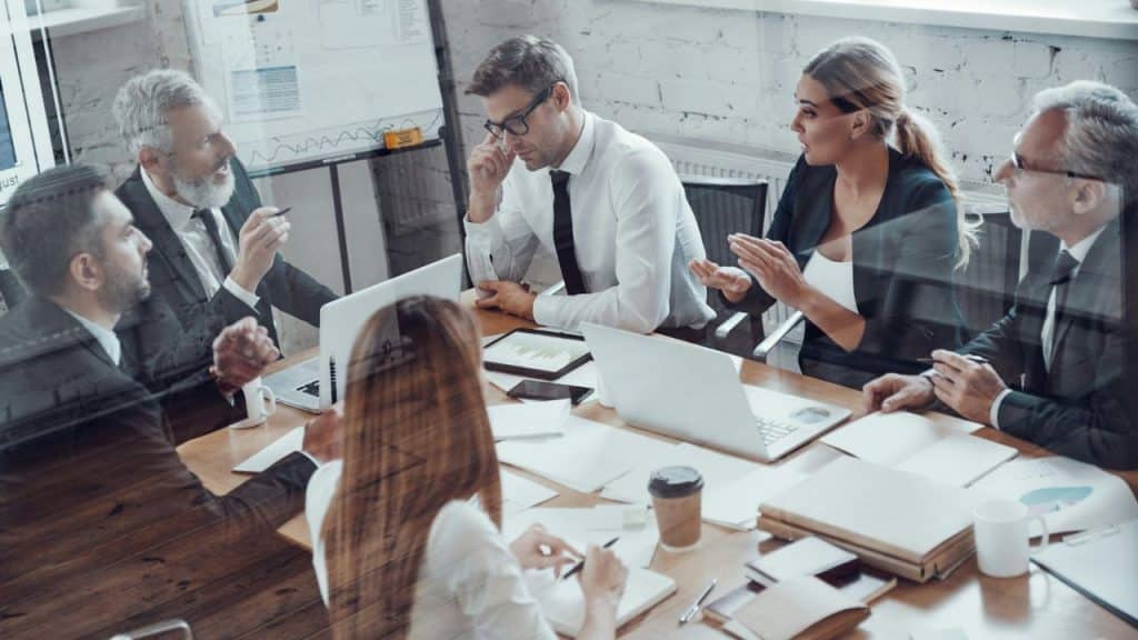 A group of five professionals are engaged in a dynamic discussion around a conference table.