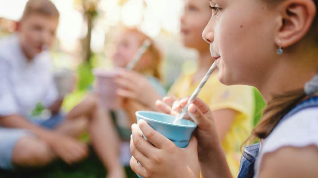 A group of children sipping drinks through straws outdoors.