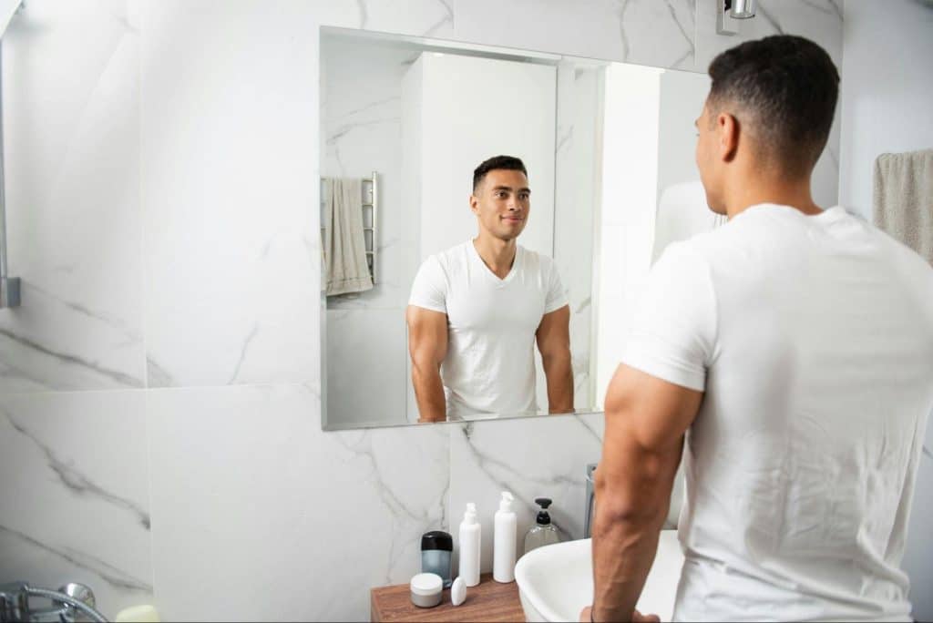 A man looking at the mirror feeling content.