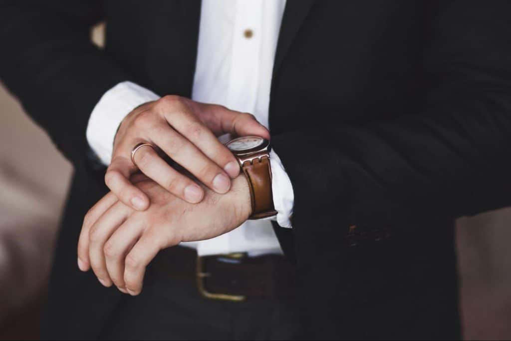 A man with his watch representing “show up on time”.