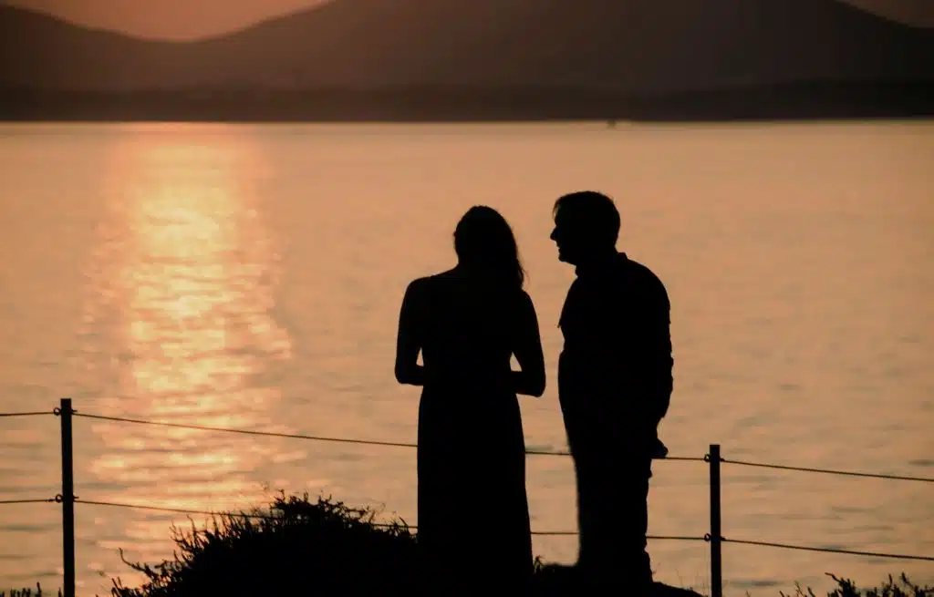 A man and woman standing in front of the lake