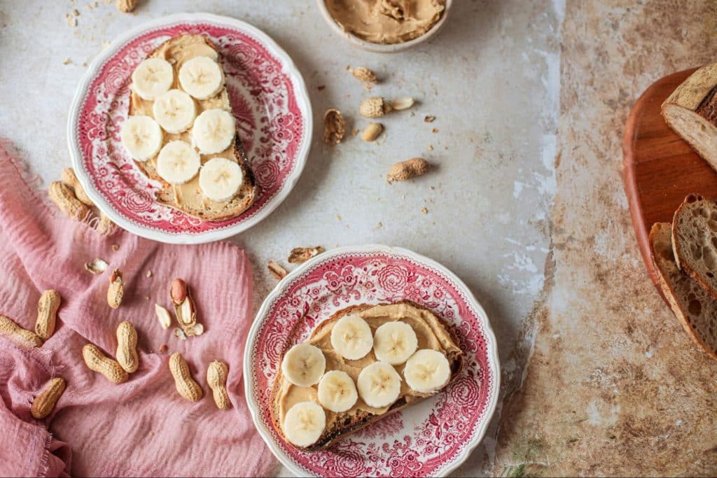 A picture of banana and a peanut butter on a bread.
