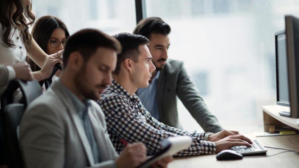 A group of colleagues collaborating around a computer workstation.