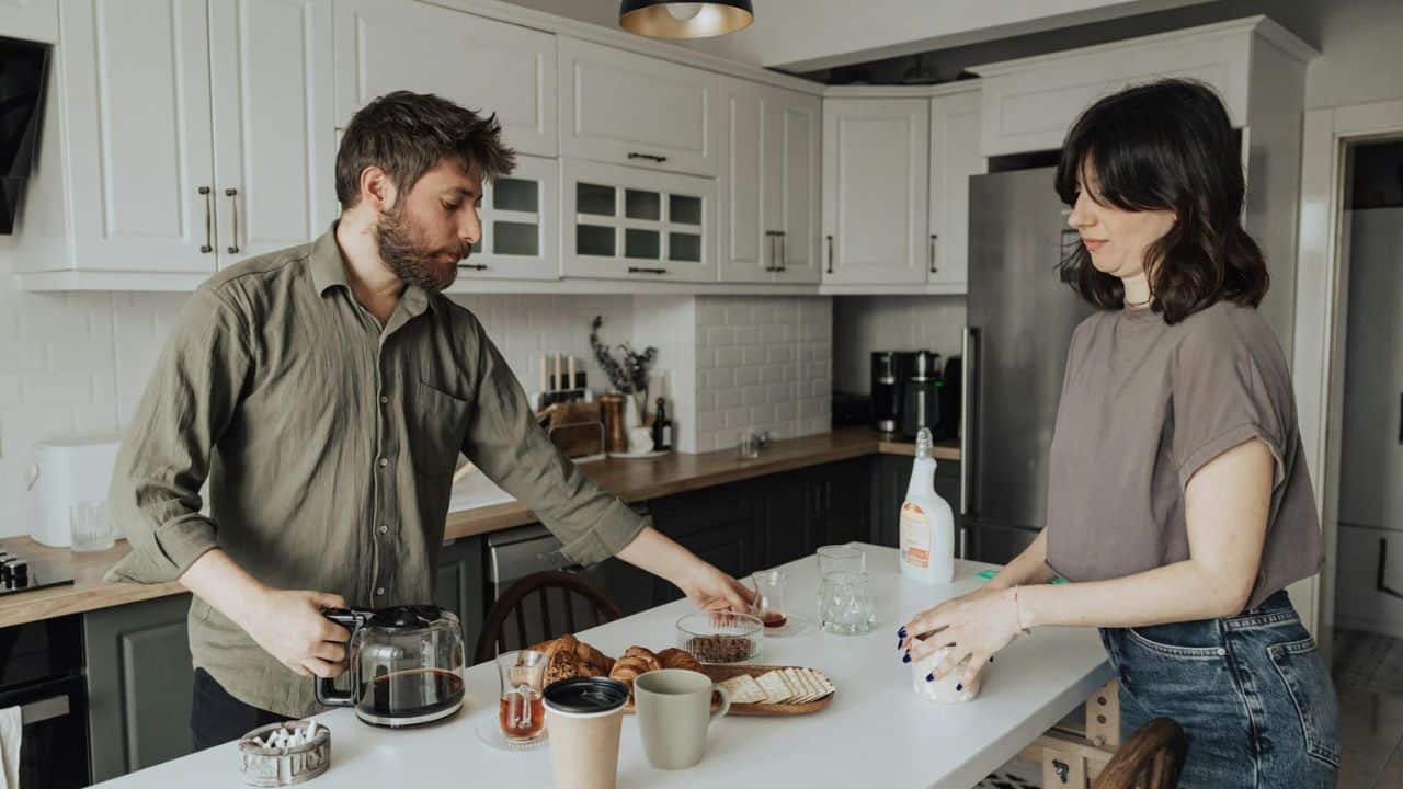 A man and woman prepare breakfast together in a bright, modern kitchen.