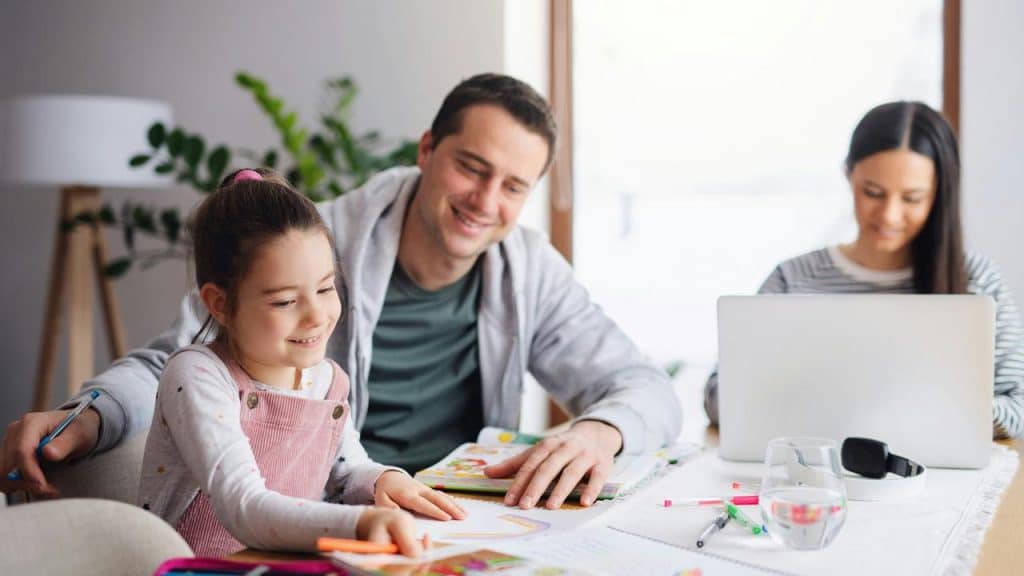 A girl coloring at a table with her parents.