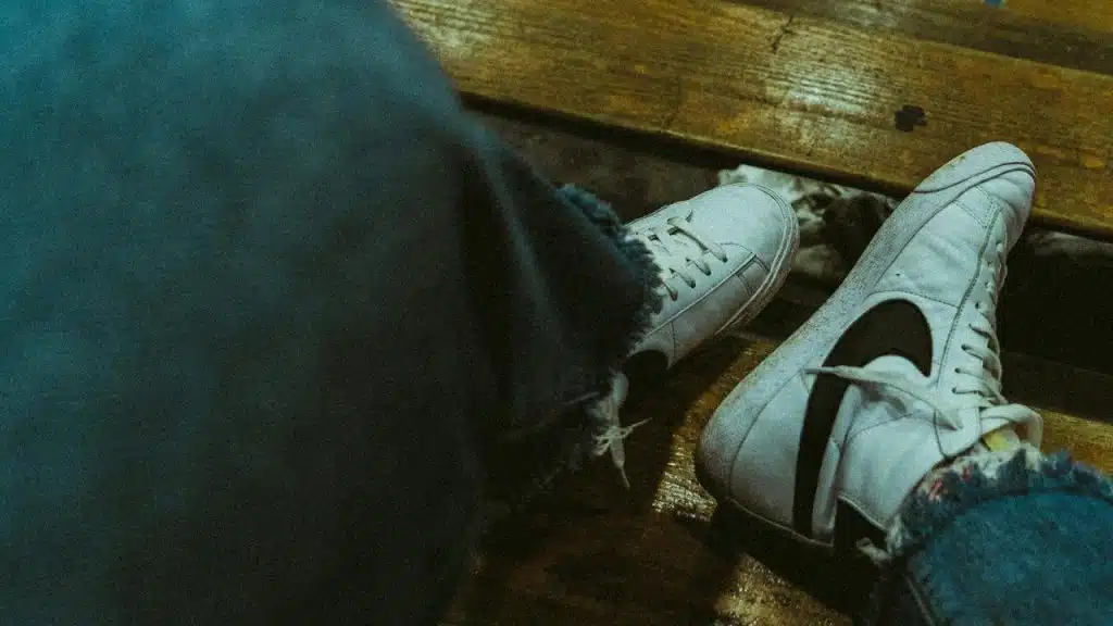 A pair of white sneakers resting on a wooden bench.