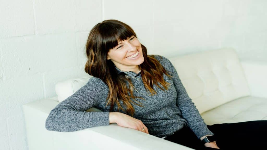 A woman smiling while sitting on a couch.