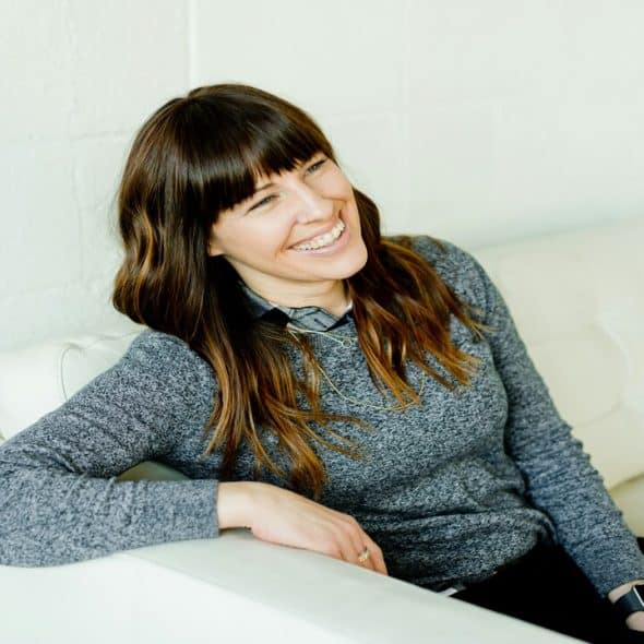 A woman smiling while sitting on a couch.