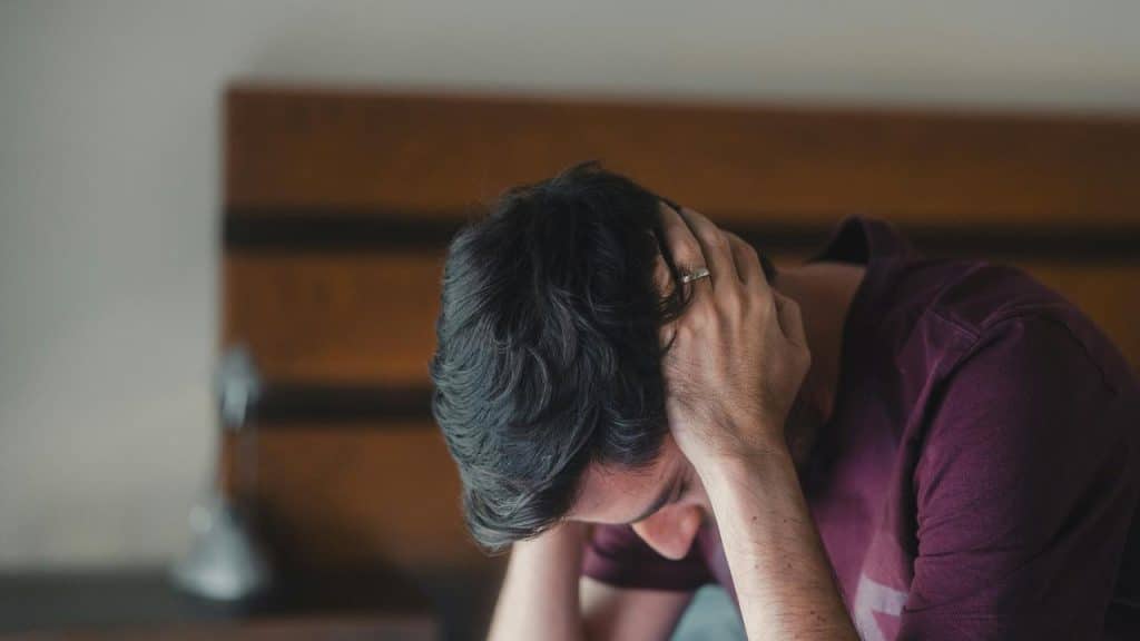 A man with his head in his hands, looking distressed.