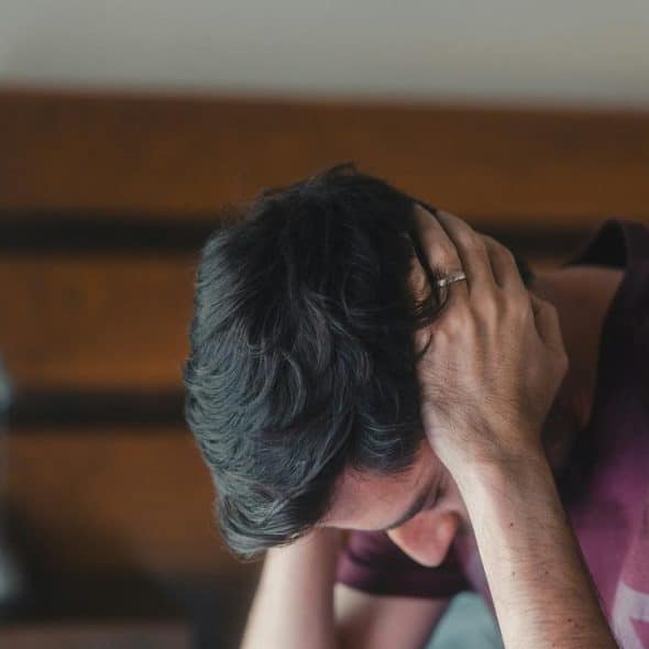 A man with his head in his hands, looking distressed.