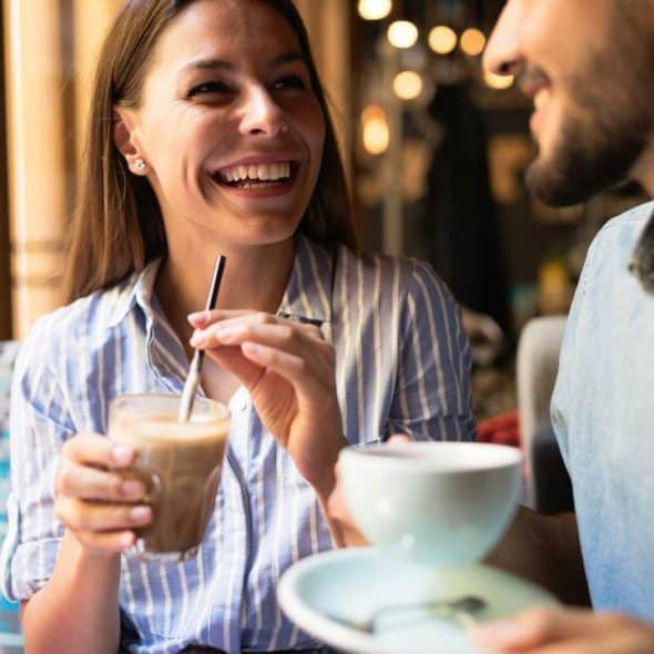 A smiling woman and man drinking coffee.