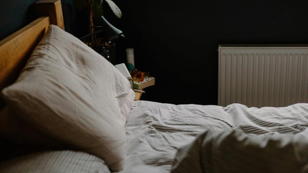 An unmade bed with a pillow.