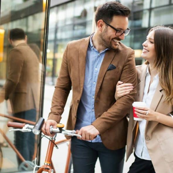 A Man smiling at a woman while holding a bicycle.
