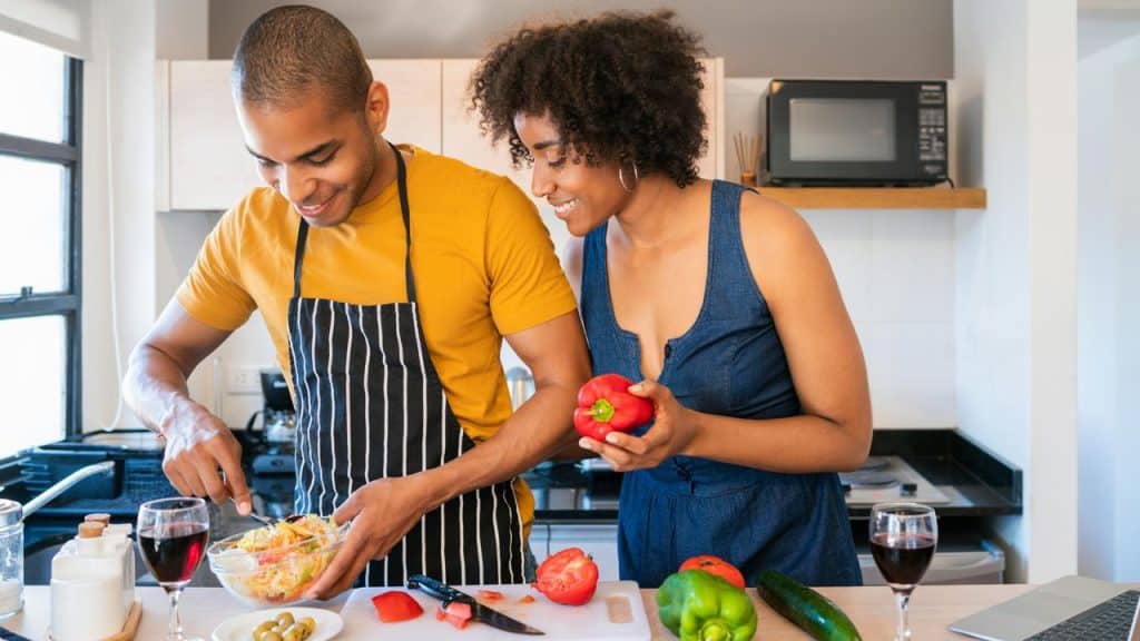 A couple preparing a salad together in a kitchen.