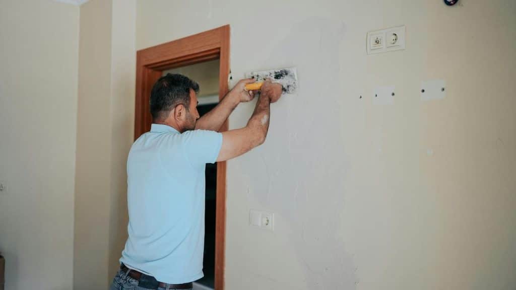 A man plastering an interior wall with a trowel.