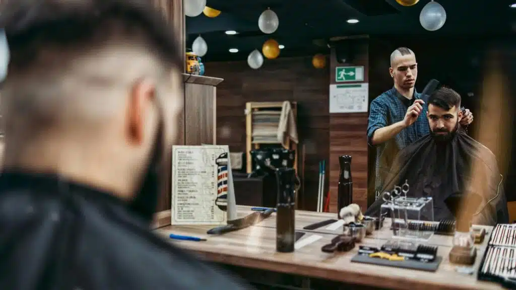 A barber trimming a customer’s hair in a shop.