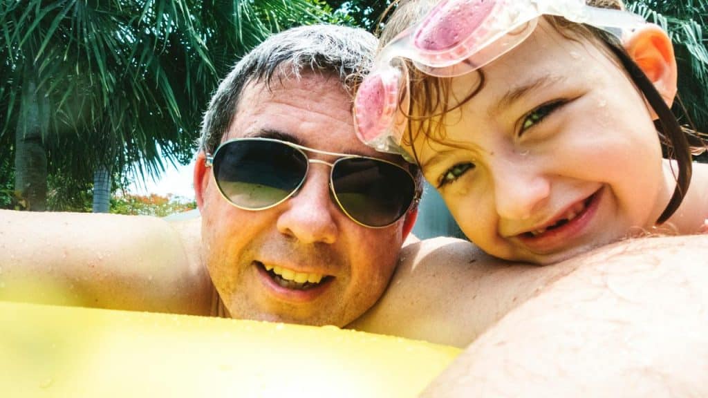 A man and child smiling on a pool float.