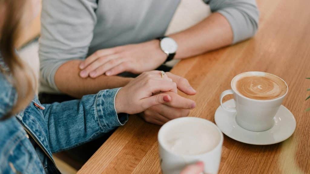 A couple holding hands over two coffee cups.