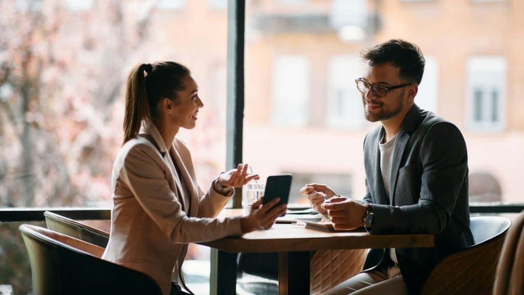 A man and woman sit at a table, smiling and engaged in conversation.