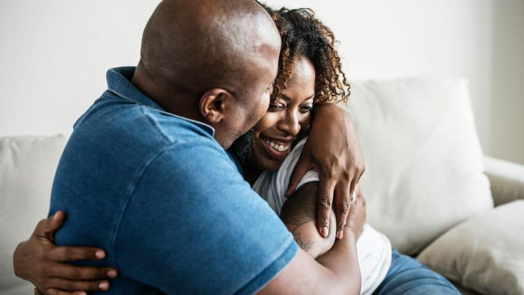 A couple hugging on a couch.