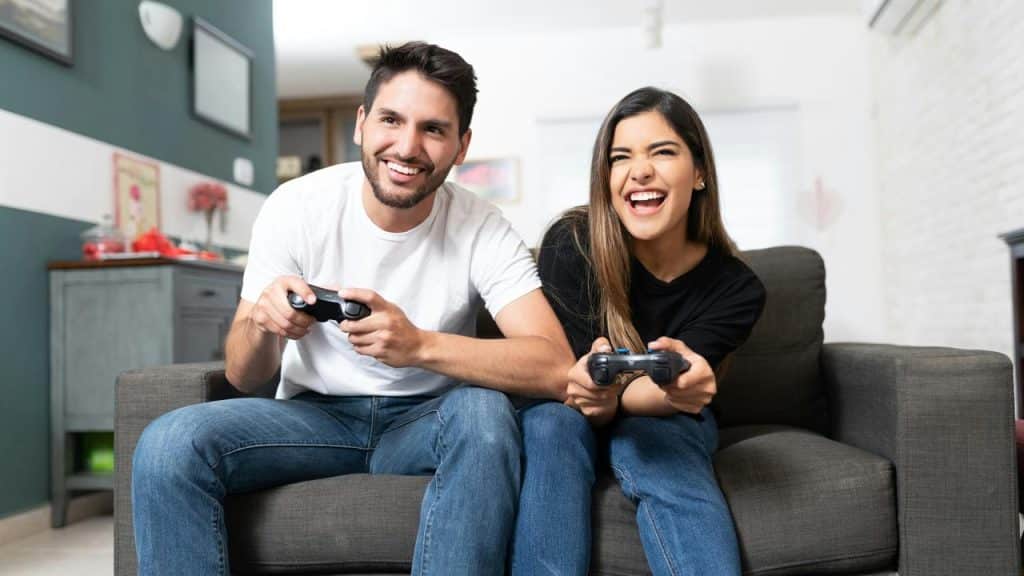 A couple playing video games on the couch.