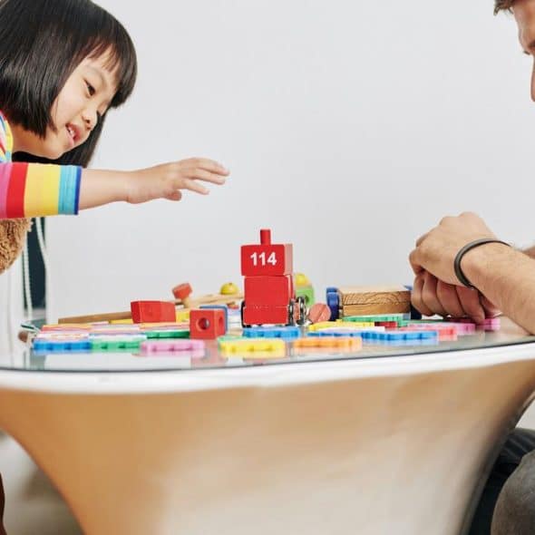 A girl and a man playing with wooden blocks.